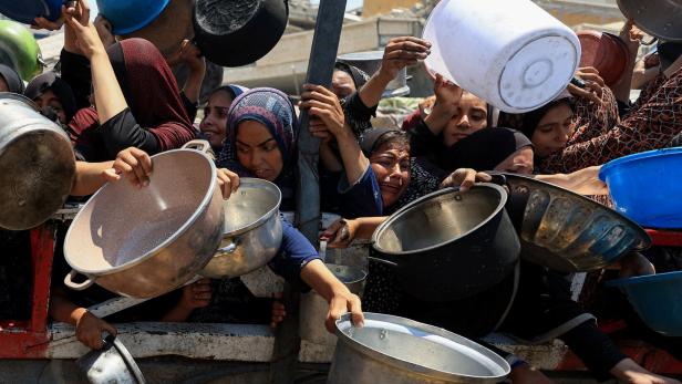 Palestinians gather to receive food from charity kitchen, in Gaza City