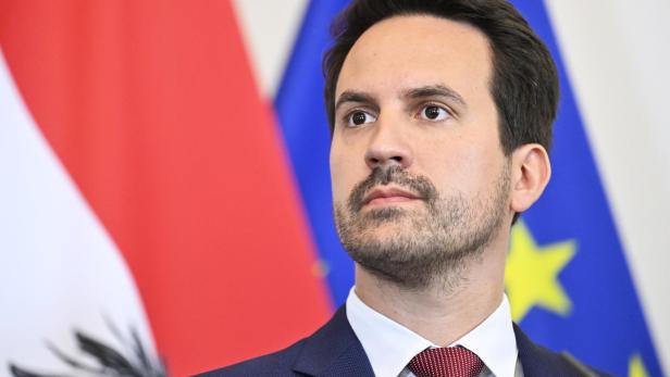 Alexander Schallenberg vor den Flaggen Österreichs und der EU.