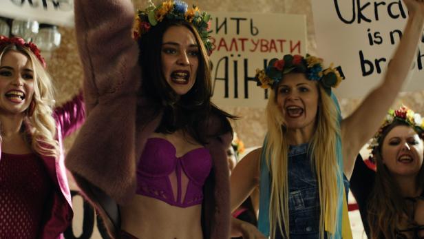 Frauen mit Blumenkränzen demonstrieren mit Plakaten im Stil der Slutwalk-Bewegung.