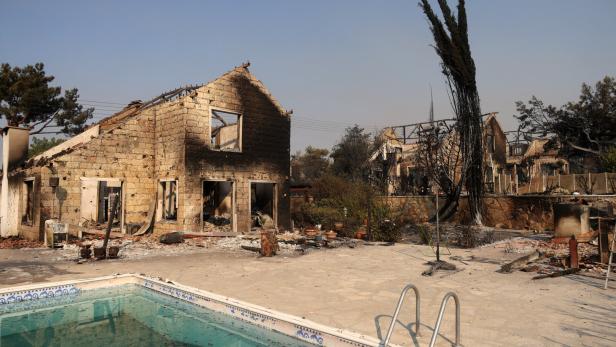 A burnt house is seen, as a wildfire burns in the village of Souni, near Limassol