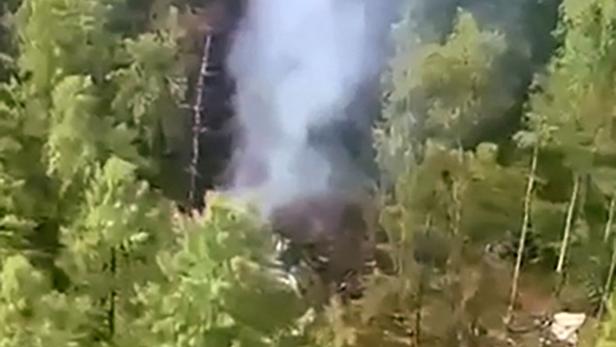 RUSSIA-PLANE-ACCIDENT Ein Flugzeugwrack raucht inmitten eines dichten Waldes.