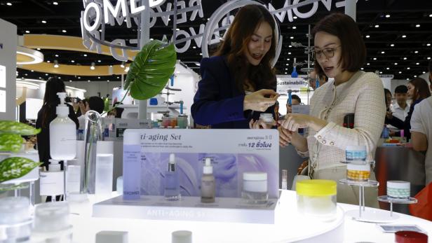 Zwei Frauen betrachten auf der Cosmoprof CBE ASEAN in Bangkok Anti-Aging-Produkte.