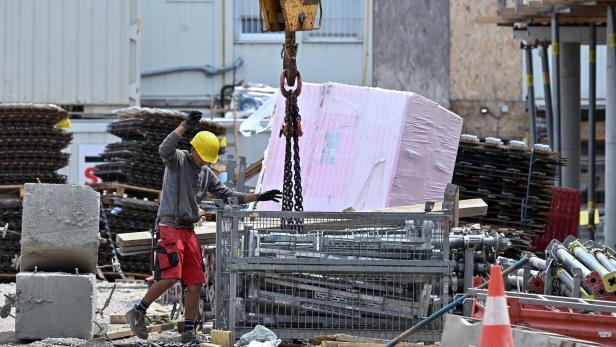 Bauarbeiter auf einer Baustelle unter einem Kran.