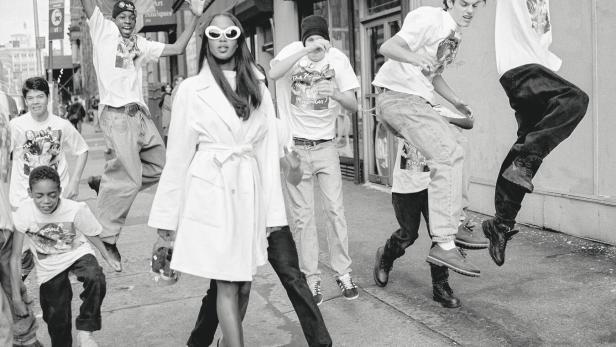 Naomi Campbell auf der Straße, rundherum springen junge Männer und Buben mit Baggy-Pants