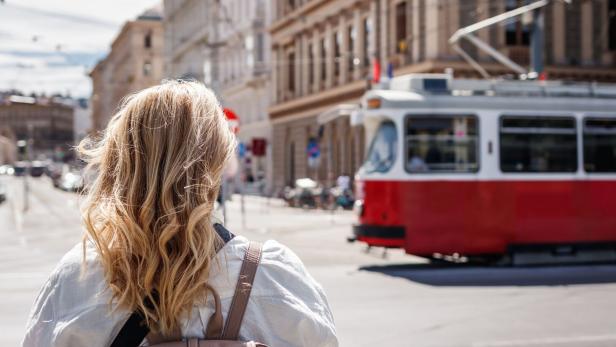 Woman tourist looking at passing tram in Vienna, Austria