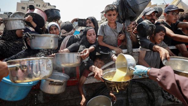 Palestinians wait to receive food from a charity kitchen, in Gaza City