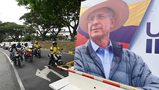 COLOMBIA-POLITICS-JUSTICE-URIBE Eine Gruppe von Motorradfahrern fährt an einem Wahlplakat von Uribe in Kolumbien vorbei.