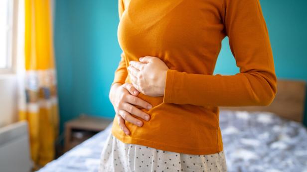 Frau hält sich den schmerzenden Bauch.