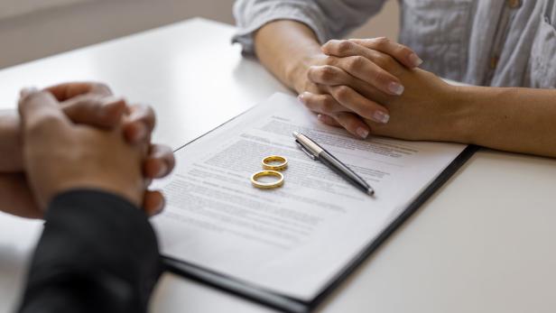 Partner sitzen gegenüber am Tisch liegt ein Vertrag