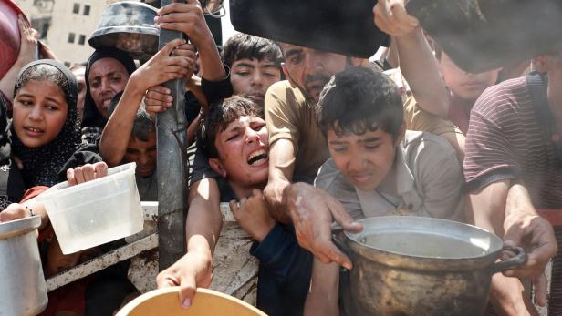 Palestinians wait to receive food from a charity kitchen, in Gaza City Palestinians wait to receive food from a charity kitchen, in Gaza City