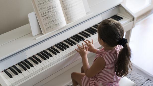 Cute little girl playing piano at home