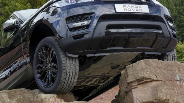 Ein schwarzer Range Rover klettert über einen Steinhaufen.
