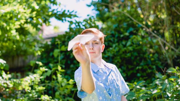 Teenage Boy Throwing Paper Airplane