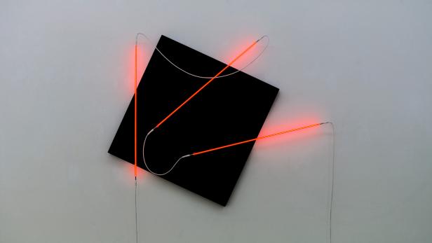 Eine schwarze, quadratische Form mit roten Neonröhren an einer Wand.