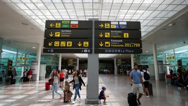 FILE PHOTO: People walk under a sign at Barcelona-El Prat airport