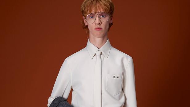 Ein Mann mit Brille hält eine grüne Gucci Reisetasche.