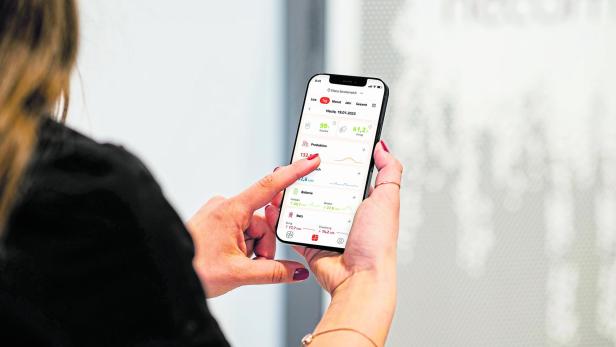 Frau hält Smartphone mit Neoom-App.