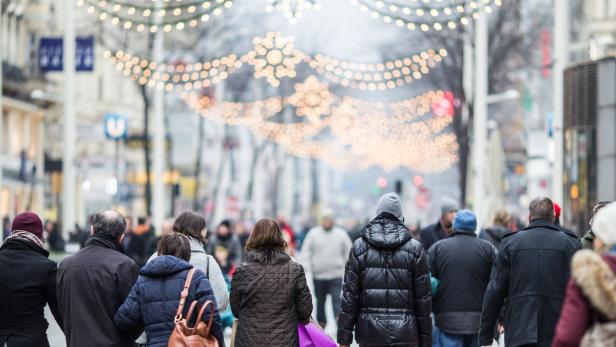 Menschen gehen eine mit Lichtern geschmückte Straße entlang.
