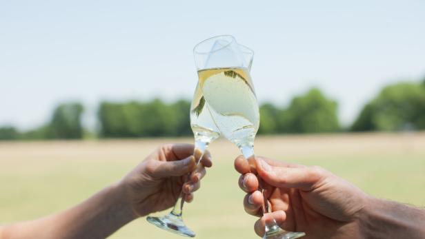 Ein Paar stößt mit Champagnergläsern im Freien an.