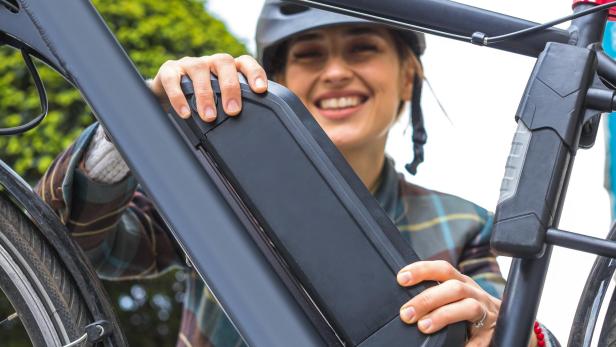 Eine Frau wechselt den Akku ihres E-Bikes aus.