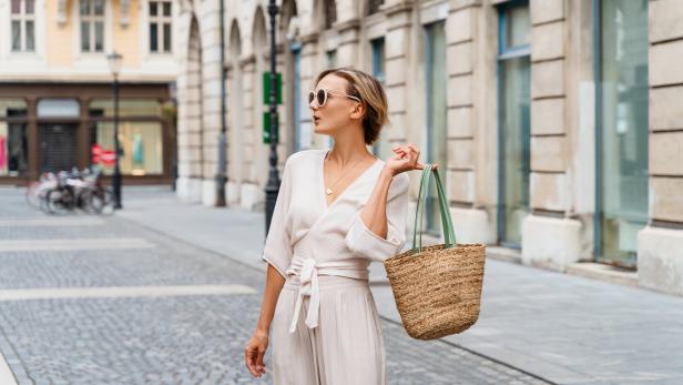 Eine stilvoll gekleidete, gut gelaunte Frau erkundet eine europäische Altstadt.