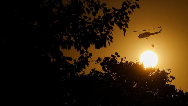 Firefighting helicopter flies past the sun after attending to a fire in Cape Town