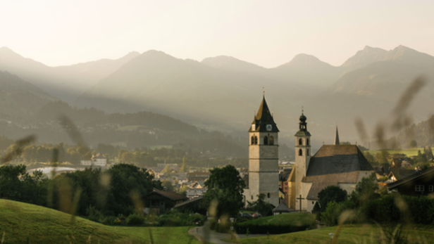 Eine Kirche in den Bergen, umgeben von majestätischen Gipfeln und üppigem Grün.