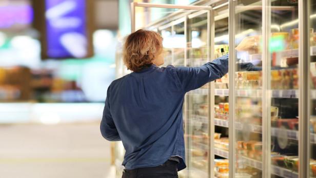 Man choosing frozen food from a supermarket freezer.