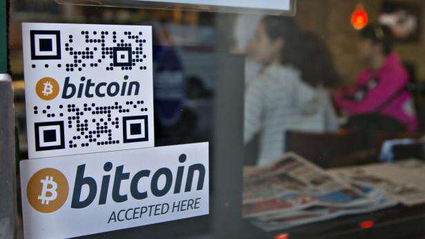 Signs on window advertise bitcoin ATM machine that Aufkleber mit dem Bitcoin-Logo und einem QR-Code an einem Fenster.