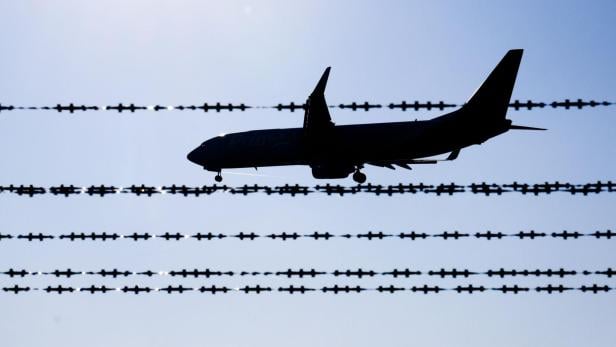 ++ ARCHIVBILD ++ Symbolbild Abschiebung Die Silhouette eines Flugzeugs ist hinter einem Stacheldrahtzaun zu sehen.