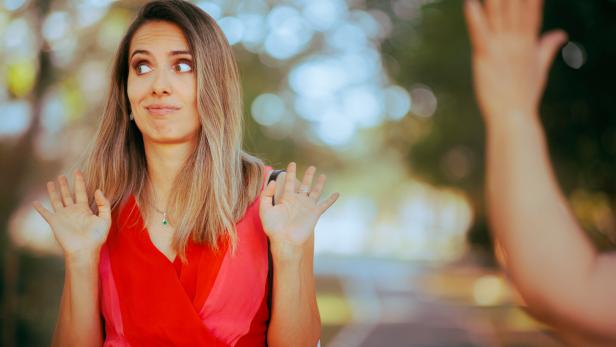 Eine Person tut so, als ob sie jemanden nicht sieht, der winkt und grüßt.
