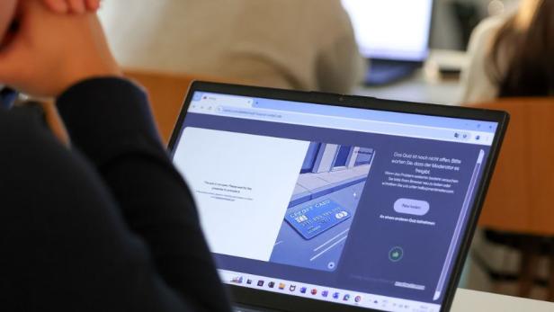 Ein Kind sitzt vor einem Laptop in einer Schulklasse.