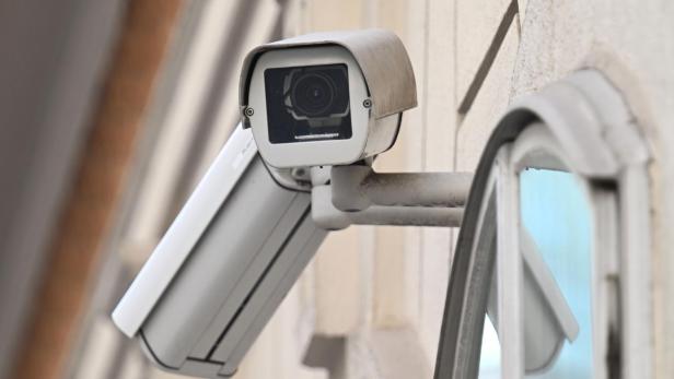 Eine Überwachungskamera ist an einer Wand neben einem Fenster montiert.