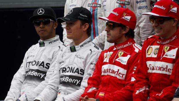 Mehrere Formel-1-Fahrer von Mercedes und Ferrari sitzen nebeneinander.