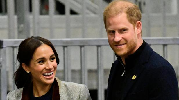 Harry und Meghan lächeln in die Kamera.