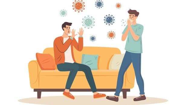 Man sits on the sofa and is afraid of viruses from a sneezing or coughing person passing by. Virus attack, epidemic concept.
