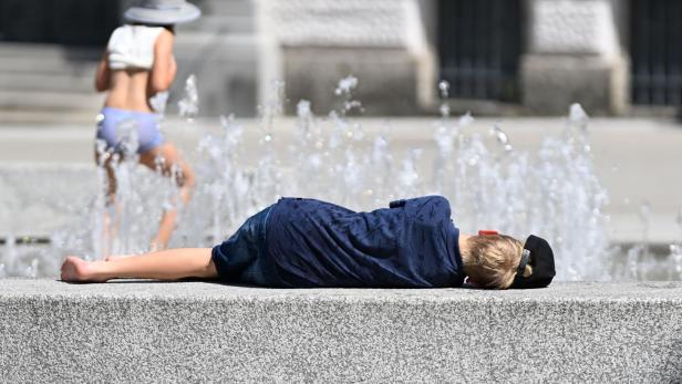 Blonde Frau liegt neben einem Brunnen