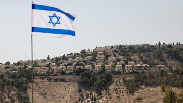 Israeli flag flutters, as part of the Israeli settlement of Maale Adumim is visible in the background, in the Israeli-occupied West Bank