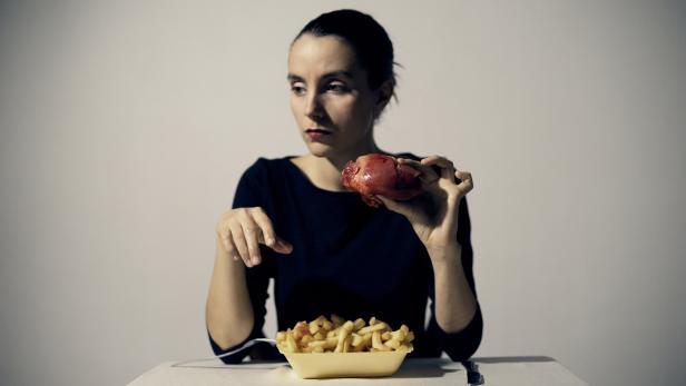 Die Künstlerin hinter einer großen Schale Pommes Frites - dazu hält sie ein (wohl künstliches) Herz in der Hand