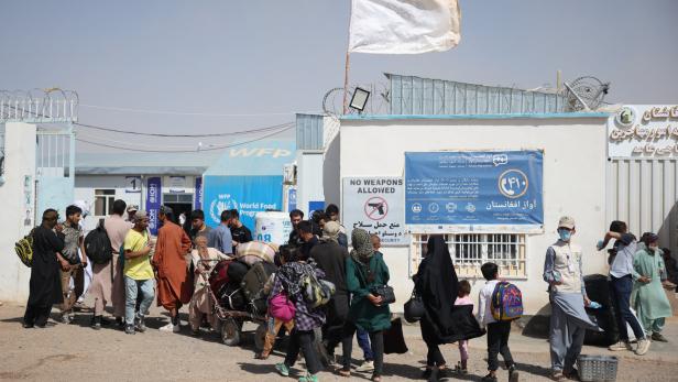 Afghan nationals deported from Iran walk toward a camp set up for returning migrants near the Islam Qala border crossing
