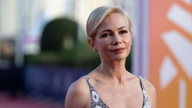 Schauspielerin Michelle Williams lächelt in die Kamera. Sie trägt ein ärmelloses Oberteil.