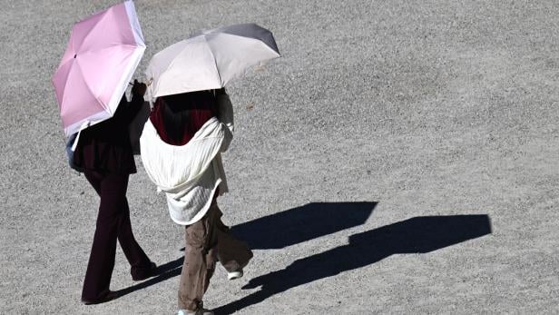 Zwei Spaziergänger mit Sonnenschirmen