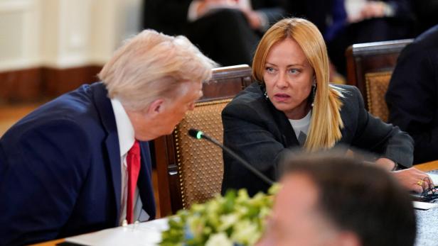 Donald Trump sitzt neben Giorgia Meloni vor einem Mikro.