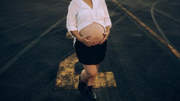 Schwangere legt ihre Hände auf den Bauch