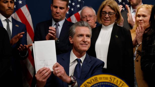Der kalifornische Gouverneur Gavin Newsom hält einen unterschriebenen Zettel zur Neuordnung der Wahlkreise hoch