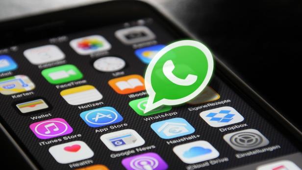 Symbolbild: WhatsApp-Logo über einem Smartphone-Display.