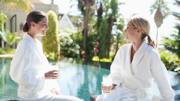 Two women relaxing in bathrobes by a pool