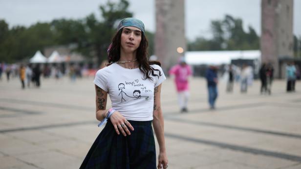 Künstlerin Canel Aylin steht mit einem Seidentuch im Boho-Look, am Hinterkopf verknotet, auf einem Platz in Berlin.