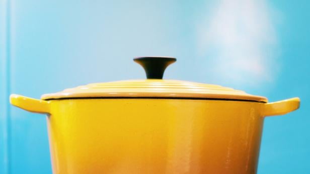 Yellow lidded pot steaming on lit gas stove