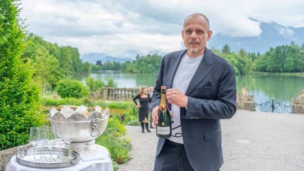 Gery Keszler mit einer Flasche Champagner in der Hand